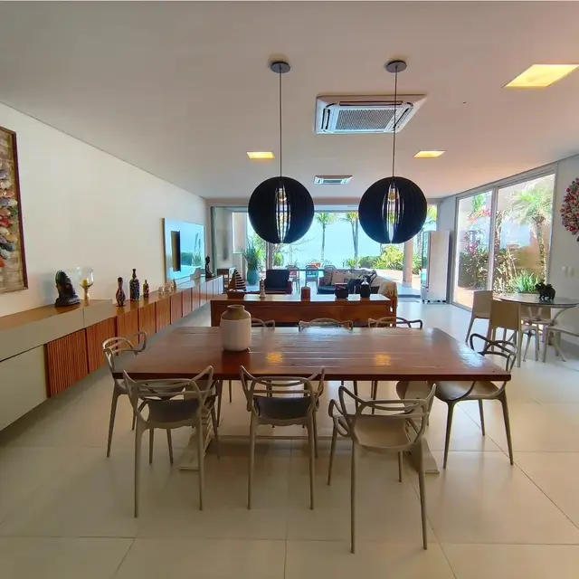 Sala de jantar integrada à sala de estar, com vista para a piscina e o mar ao fundo