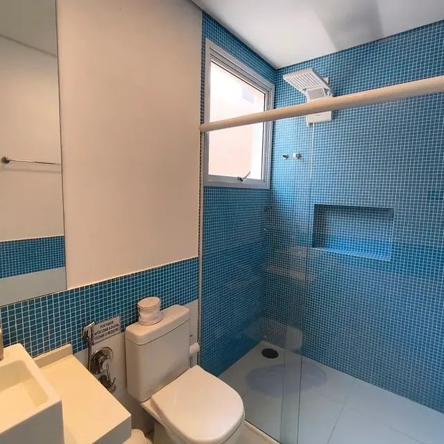Banheiro com box de vidro e revestimento em pastilhas azuis