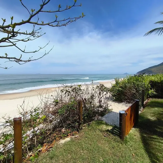 Portão de acesso direto à praia, com areia e mar ao fundo