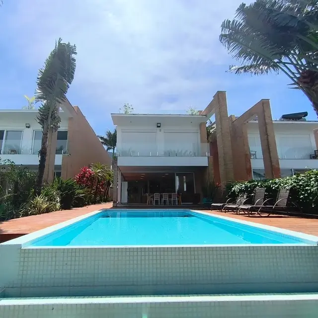 Fachada da casa vista da piscina, com varandas e área externa arborizada